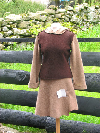 Zweiteiliges Ensemble aus naturbelassener Schafwolle. Ein ärmelloser Pullover in brauner Farbe wird über einem beigefarbenen, langärmeligen Rock getragen.