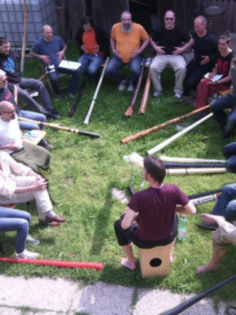 Top view on workshop participants sitting in a circle around Ansgar Stein.