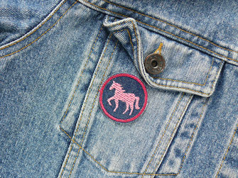 Aufnäher mit kleinem gestickten rosa Pferd als Aufbügler auf einer Jeansjacke