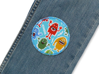 eine Jeanshose wurde mit einem Hosenflicken mit kleinen Monstern repariert