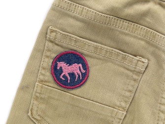 kleiner Aufnäher mit gesticktem rosa Pferd als Accessoire auf eine Jeans aufgebügelt
