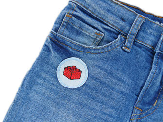 auf eine Jeanshose ist ein hellblauer Patch mit gesticktem roten Legostein aufgebügelt