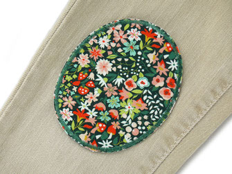 !B auf eine helle Jeanshose ist ein Blumen Bügelflicken aus Bio Baumwolle als Flicken aufgebügelt
