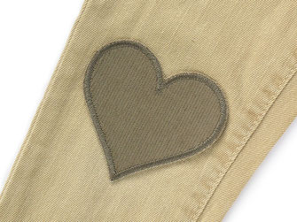 hellbrauner Herz Cordflicken ist aufgebügelt auf heller Jeanshose als Flicken zum Reparieren von Hosenlöchern