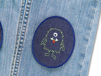 ovale Jeansflicken mit aufgesticktem grünen Monster repariert als Flicken eine Kinderhose