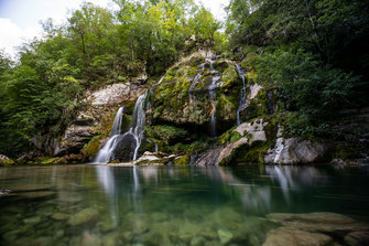 Das Wasser des malerischen Virje Wasserfalls fließt über moosbewachsene Felsen in ein Becken.