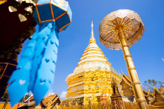 Un templo dorado con una linterna azul en primer plano en Chiang Mai.