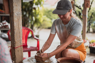 Eine Frau sitzt an einer Töpferscheibe im Thanh Ha Pottery Village und töpfert ihre eigene Tasse.