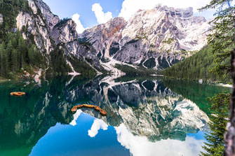 Pragser Wildsee mit spiegelnden Wasser und umgeben von hohen Bergen.