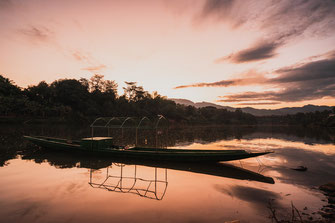 Un vieux bateau de pêche au coucher du soleil sur le Mékong.
