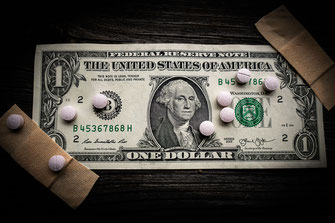 Ein Dollar mit Pflaster und Tabletten als Darstellung für eine Krankenversicherung.