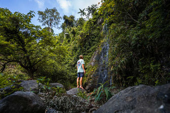 A man stands by the Kaen Nyui waterfall and looks up at the sky.