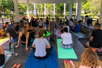 Eine Gruppe von Menschen sitzt auf Matten und macht Yoga.