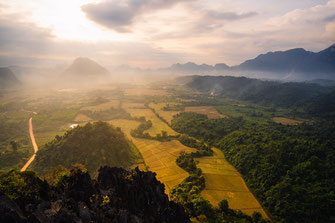 Drohnenaufnahme von Reisfeldern und den umliegenden Bergen von Vang Vieng.