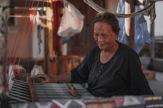 Eine alte Frau sitzt an einen Webstuhl im Dorf Ban Xang Hai.