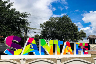 Letras de colores con el nombre de la ciudad de Santa Fé y árboles verdes de fondo.