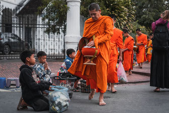 供養に向かうオレンジ色の服を着た僧侶たち。