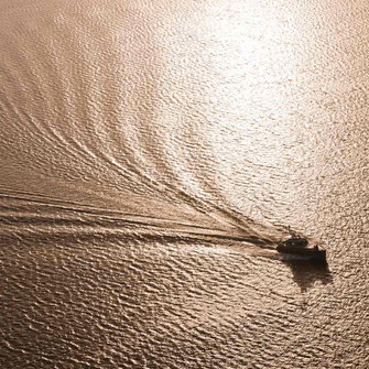 Luftaufnahme einer Motoryacht auf dem Meer in der goldenen Abenstimmung.