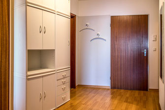Großzügiger Wohnungseingangsbereich mit einem grossen Schrank mit viel Stauraum, Garderobe, Spiegel und Abseite mit Regal