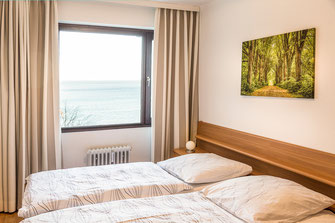Großes Schlafzimmer mit 2 Betten mit getrennenten Matratzen, 2 Nachttische, Blick auf die Ostsee