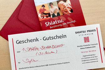 Geschenkgutschein für eine Shiatsu-Behandlung mit Informationsbroschüre zu Shiatsu und dunkelroter Briefumschlag
