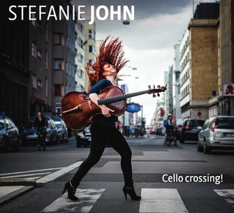 Rothaarige Cello-Spielerin überquert mit ihrem 5-Saiter die Friedrichstrasse in Berlin - CD von der Cellistin Stefanie John mit instrumentaler Musik und Songs in Zusammenarbeit mit Künstlern verschiedener Genre