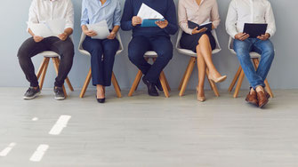 Mehrere Business-Personen im Anzug gehen selbstbewusst auf die Kamera zu - symbolisch für professionelle Auswahl von Führungskräften im Unternehmen.