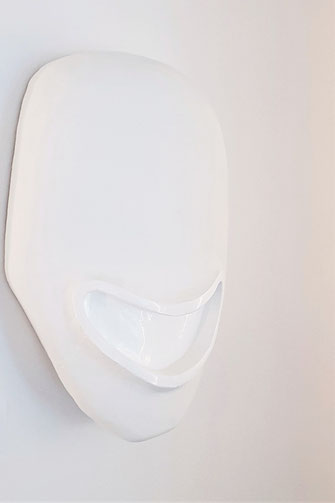 Die Skulptur Into the great wied open von Oliver Braig sieht aus wie eine Maske ohne Augen und Nase und einem weiten, offenen Mund. Die Maske ist aus Holz und matt weiß. Der Mund und die Mundöffnung sind hochglanz weiß. Ist das Lachen freundlich oder fies