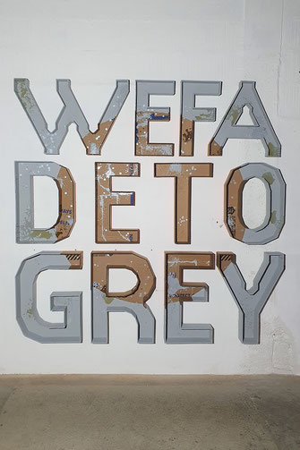 WW FADE TO GREY. On the efficiency of grey. Was ist das mit unserer Gesellschaft? Oliver Braig hält uns wieder einmal einen Spiegel vor. In der Mitte der Arbeit entstet durch optische Täuschung ein brauneer Kreis. Die Buchstaben aus Karton, sind mit der o