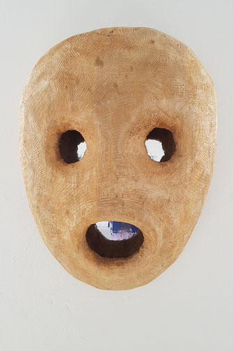 Eine Gesicht, wie eine Maske ohne Nase, mit Löcher als Augen und Mund, aus Holz, im Innern ein Spiegel aus Folie. MASK ist der Titel dieser Holzskulptur. Ein Schreckmoment? Anhalten des Atems? Was ist passiert? Was geht hier vor? Was geht im Innern vor? 