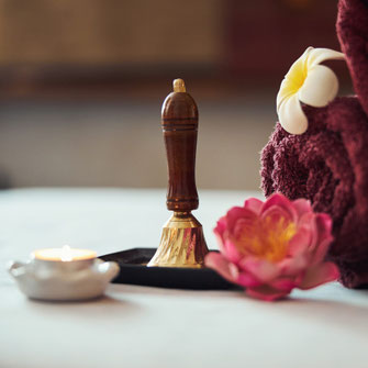 Massage-Utensilien mit Blüte, Kerze und Thai-Massage-Stempel im Studio