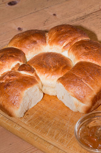 Französisches Brioche als Kranz angebrochen auf Holzbrett