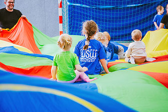 Kinder und Eltern spielen mit einem großen bunten Tuch beim Familiensport des WSW Rostock