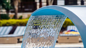 Wasser kommt aus einem Schwall der am Beckenrand montiert ist
