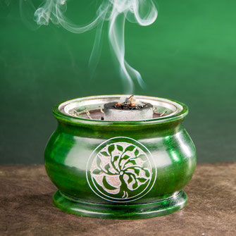 Grünes Netzgefäss aus Stein mit Räucherkohle auf dem Netz