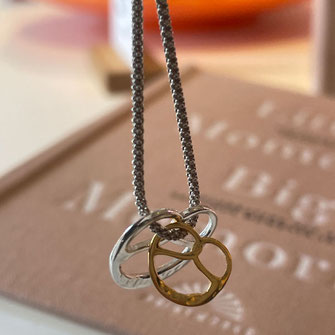 Food Jewelry Brezel. Zwei Brezel-Schmuck-Anhänger in einer Detailaufnahme 'doppelte Brezel'-Liebe- Halskette' gefertigt in Handarbeit in Stuttgart.DEIN Stuttgart Souvenir.