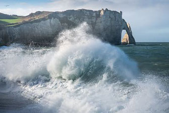 Vue panoramique des Falaises d’Etretat, avec leur célèbre arche naturelle et leur phare solitaire.