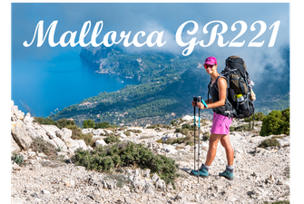 Wanderin auf dem GR 221 im Tramuntana-Gebirge Mallorcas mit Blick auf die Trockensteinmauern und die mediterrane Berglandschaft