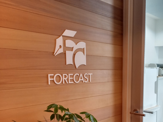 写真：事務所入口。壁にFORRCASTのロゴが飾られている