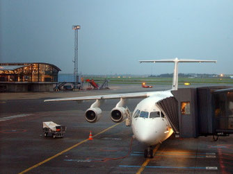 Ein Flugzeug der SAS Scandinavian Airlines ist am Hangar des Flughafens Kopenhagen angedockt. Im Hintergrund ist ein von innen beleuchtetes Gate zu erkennen.