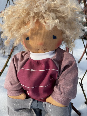 Die Puppe ist nach Art der Waldorfpuppen in Handarbeit hergestellt sie hat ein liebes Gesicht und lockige Haare sowie schöne farbige Puppenkleidung an.
