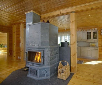 Ein Specksteinofen in der Mitte des Blockhauses teilt die Wärme gleichmäßig - © Blockhaus Kuusamo