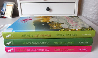 Alle drei Bände "Kat & Co." liegen aufeinander. Band eins hat einen pinkfarbenen Rücken, Band zwei einen dunkelgrünen, Band drei einen hellgrünen.