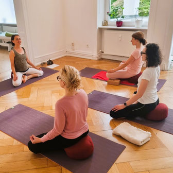 Sitzende Teilnehmende während der Atem- und Achtsamkeitsübung im Yogakurs in Wiesbaden