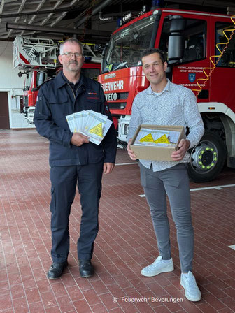 Hauptbrandmeister Mario Bönning freut sich über die 600 Kinderfinder, die ihm Maurice Rolf von der Mecklenburgischen Versicherungsgruppe übergeben hat.