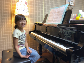 水戸市のまりピアノ教室の生徒さんがピアノの前で笑っている