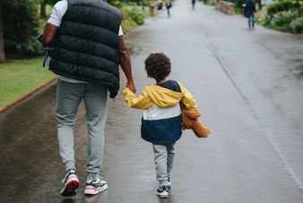 Kind und Vater Hand in Hand auf einer Straße