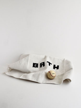 リサイクル糸を使ったPUEBCOの手織りバスマット。ホワイトの「BATH」ロゴ入りで、手仕事ならではの温かみと清潔感をバスルームに添えます。