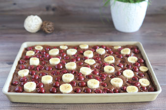 Kirschen und Bananen über den Teig verteilen