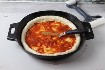 Pizzasoße mit dem kleinen Streicher verteilen